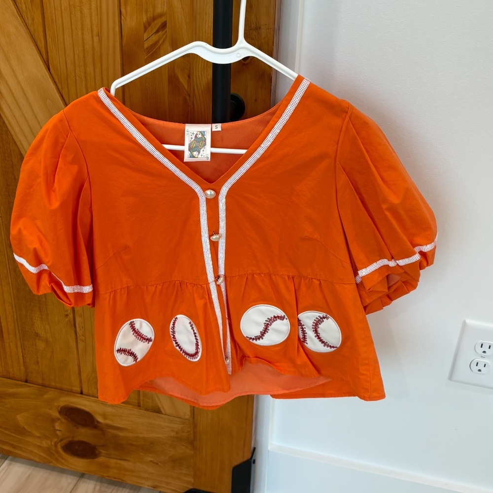 QUEEN OF SPARKLES PEPLUM BASEBALL TOP ORANGE